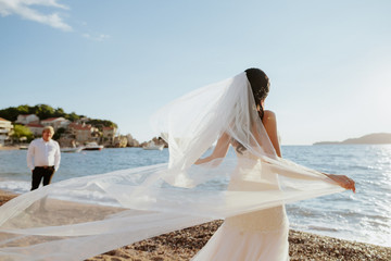 Fototapeta na wymiar Bride in beautiful dress on beach with sea view