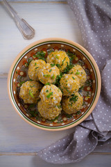 Bowl of meatballs with rice and vegetables on white wooden table