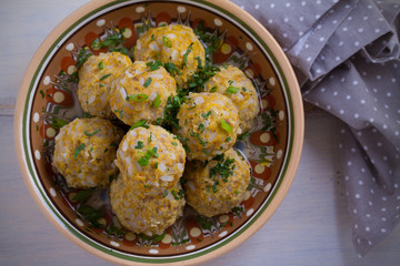 Bowl of meatballs with rice and vegetables on white wooden table