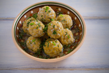 Bowl of meatballs with rice and vegetables on white wooden table