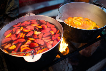 Hot gluhwein or mulled wine in a cauldron at fair, local treat, warm and spicy. A hot wholesome traditional citrus drink on fair. Vitamins in the winter festival.