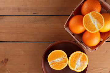 Oranges in a wooden box on a wooden background, citrus in retro style, copy space, orange fruit on a clay plate, tropical fruits in a box on a table, half orange for a vegan