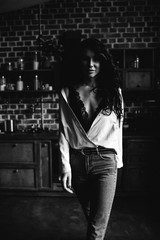 Fototapeta na wymiar Beautiful brunette in the kitchen, modern housewife, fashion, wooden brown furniture, dressed in blue jeans and a blue shirt