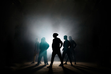 silhouette of group breakers dancing headed by leader on stage