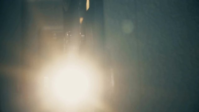 Vintage 8 mm film projector with lens flare and warm glow from tungsten lens. 