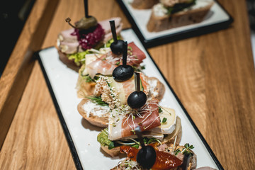 tasty pinchos with tuna, chorizos, salmon, egg, dried tomatoes, avocado, salmon, bacon, Hamon, Brie Cheese, Olives and Pesto Sauce, traditional spanish snack
