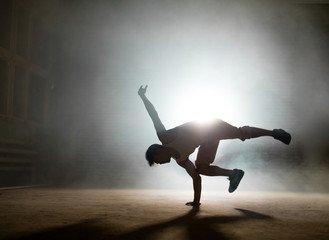 young male with short dark hair practising freeze on the ground. hardworking man. part of break dance