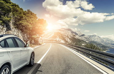 Fototapeta premium A white car rushing along a high-speed highway in the sun.