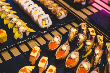 Decorated catering banquet table with different sushi rolls and nigiri sushi plate assortment on a party
