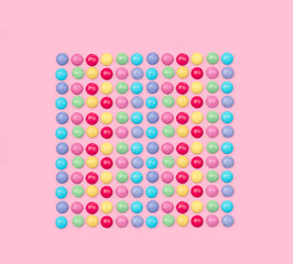 Assorted colored candies on pink background.
