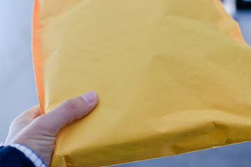 Closeup on hand with letter craft envelope on the background. Receiving and sending commercial or personal package, top view communication conceptual design