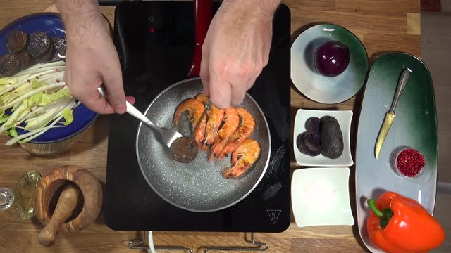Top view food preparation Shrimp and violet potatoes to the pan on the stove with induction