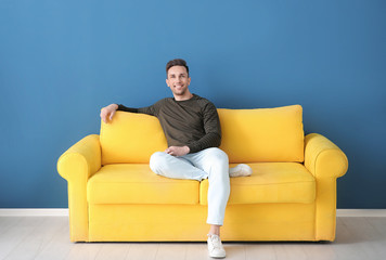 Handsome young man sitting on sofa, indoors