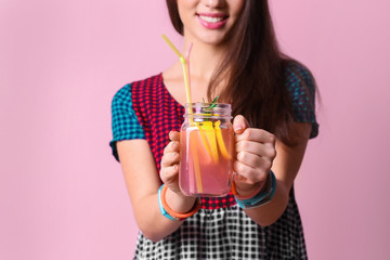 Young woman with tasty refreshing lemonade on color background