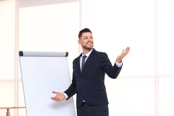 Young business trainer near flip chart, indoors