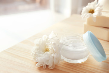 Fototapeta na wymiar Jar with body care cream and flower on table