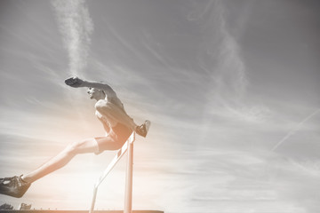 Female athlete jumping above the hurdle during the race