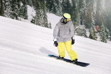 Snowboarder on ski piste at snowy resort. Winter vacation