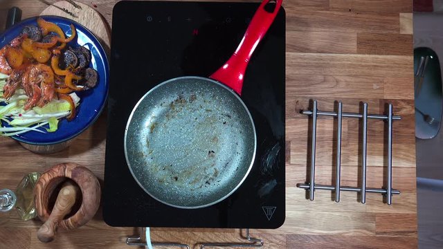 Top view food preparation Shrimp and violet potatoes to the pan on the stove with induction