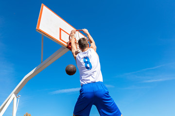 Young Basketball street player making slam dunk