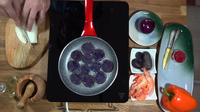 Top view food preparation Shrimp and violet potatoes to the pan on the stove with induction