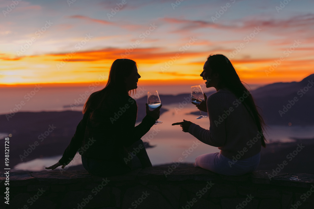 Wall mural women drink wine together at sunset - Wall murals