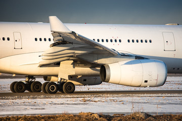 Closeup of landing gear, engine, wing, winglet and fuselage of passenger aircraft taxing on runway, side view, winter time