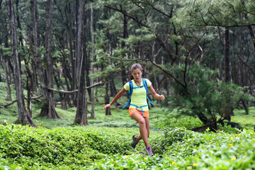 Trail runner woman athlete running jumping in forest nature mountains background. Sport girl active training difficult cardio workout outdoor in summer landscape. Focus and endurance,