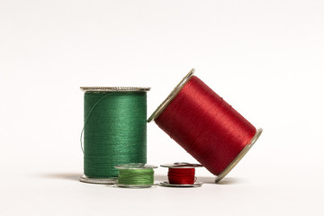 Two spools of thread with corresponding bobbins in Green and Red on a White background