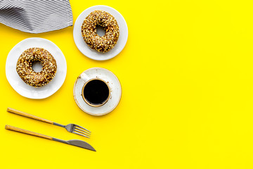 woman desk with flowers, coffee and donuts for breakfast in spring desing yellow background flat lay mock-up