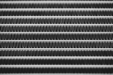 Monochrome background image of automotive radiator close up. Silver background from many duplicate...