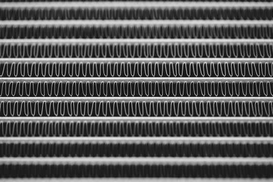 Monochrome background image of automotive radiator close up. Silver background from many duplicate lines.