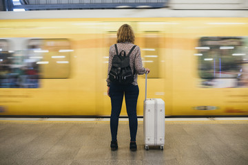 Rear view of a blond woman waiting at the train platform - Powered by Adobe