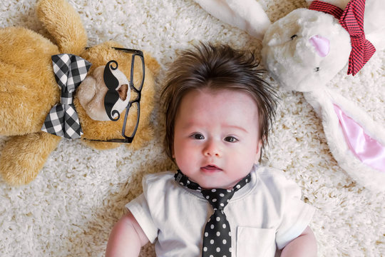 Baby Boy With His Stuffed Animals On A White Carpet