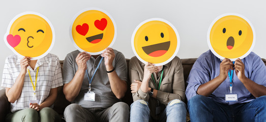 Group of co-workers holding emoticons