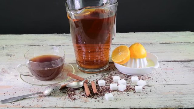 Black tea, manual squeezer with lemons. A jug of black tea and cubes of sugar.