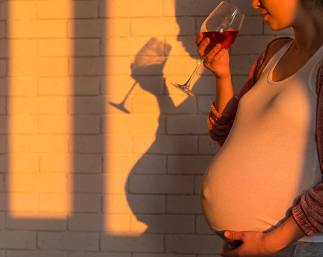 Pregnant woman with glass of red wine in hand
