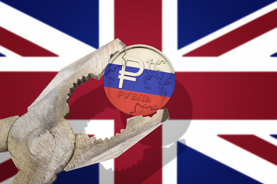 Russian ruble coin being squeezed in vice on the United Kingdom (UK) flag background. Concept anti Russian new sanctions