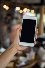 Hand holding smartphone in cafe'