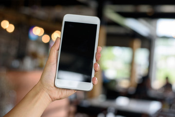 Hand holding smartphone in cafe'