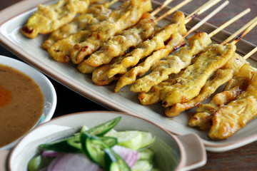 Pork satay and pickles which are cucumber slices and onions in vinegar