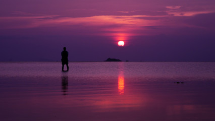 silhouette of man standing in sea at sunset