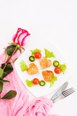 Toasts in the form of heart, cherry and cucumber on a plate. Dish served for lovers and rose. Top view