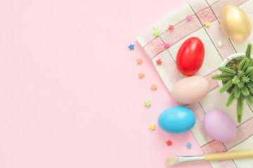 Flat lay top view colorful easter egg painted in pastel colors composition with paint brush on pink pastel color background. Easter day background top view with copy space.
