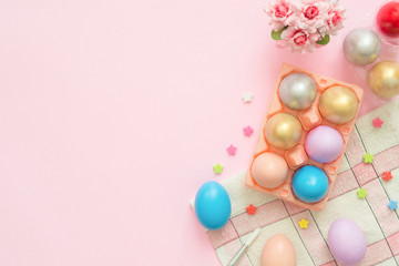 Flat lay top view colorful easter egg painted in pastel colors composition and spring flowers on pink pastel color background. Easter day background top view with copy space.