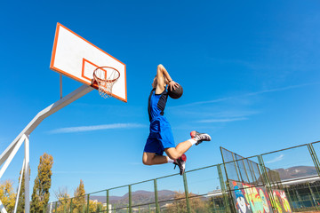 Young Basketball street player making slam dunk