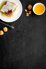 Fresh honey as dessert. Honey in bowl, honeycomb, nuts on black table top view copy space
