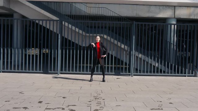 Sexy female dancer in Vogue and Waacking dance style dancing in the city with urban background.
