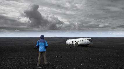 Explorer looking at plane wreck on a black beach in South Iceland