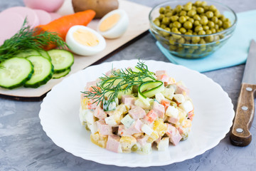 Traditional Russian salad olivier on a plate and ingredients for its preparation